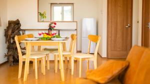 a dining room table and chairs with flowers on it at セイントY saint-Y in Motobu