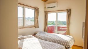 two beds in a room with a window at セイントY saint-Y in Motobu