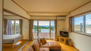 a living room with a couch and a bed and windows at セイントY saint-Y in Motobu