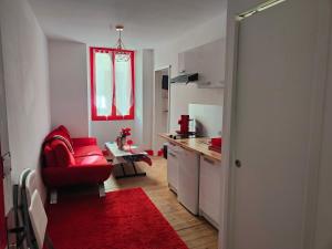 a kitchen with a red couch and a red chair at Le romantique in Argelès-sur-Mer