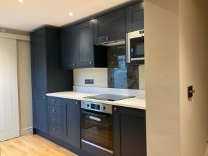 a kitchen with black cabinets and a stove top oven at Fab cottage in the heart of Deal - Great Location in Kent