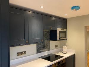 a kitchen with black cabinets and a microwave at Fab cottage in the heart of Deal - Great Location in Kent