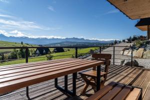a wooden deck with a bench and a view of the mountains at Nydala Eco in Rzepiska