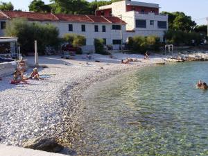 a group of people sitting on a beach near the water at House Boris in Slatine