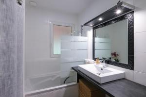 a white bathroom with a sink and a mirror at Le Logis de La Baule - Maison climatisée piscine in La Baule +16 photos