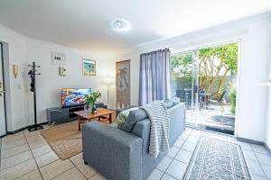 a living room with a couch and a tv at Cozy Garden Unit in Bloubergstrand in Bloubergstrand