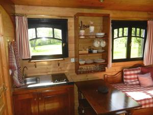 una cocina en una cabaña de madera con 2 ventanas en Les Roulottes de la Risle, en Calleville