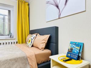 a bedroom with a bed and a book on a table at Золотой квадрат in Almaty