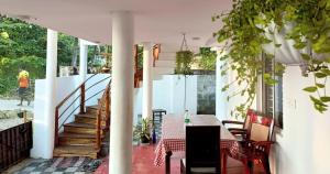 a porch with a table and chairs and stairs at Marari Praise Beachfront Homestay in Mararikulam