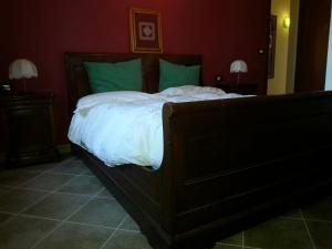 a bedroom with a large bed with white sheets and green pillows at Il GIARDINACCIO Agriturismo in LʼAquila