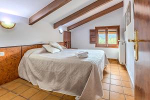 a bedroom with a bed with white sheets and a window at Can Mestrehumà in Bas +22 photos
