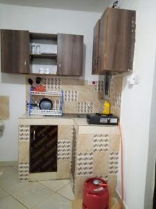 una cocina con armarios de madera y una boca de incendios roja en Esther Goodness Apartments, en Mtwapa