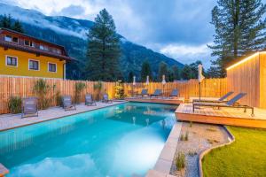 a swimming pool with chairs and a wooden fence at AlpinSpa zur Post Apartment - Bergbahn im Sommer 2025 inklusive in Bad Gastein