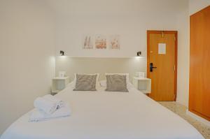 a large white bed with two pillows on it at Hotel y Apartamento Moli de Mar - Check-in 24 Horas in Lloret de Mar