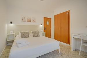 a white bedroom with a white bed and a desk at Hotel y Apartamento Moli de Mar - Check-in 24 Horas in Lloret de Mar