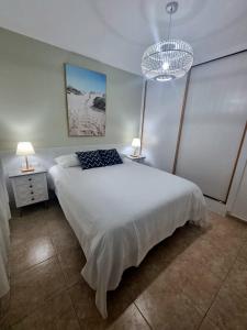 a bedroom with a large white bed with two lamps at Granillo Beach Calm in Costa Calma +15 photos