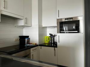 a kitchen with white cabinets and a white refrigerator at DePanne FiftyOne in De Panne