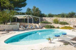a swimming pool with chairs and a stone wall at Dimora Il Mandorlo con jacuzzi riscaldata in Ostuni