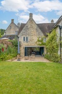 ein altes Steinhaus mit einer Terrasse im Hof in der Unterkunft Mill House & Cottage - on The Cotswold Way! in Harescombe