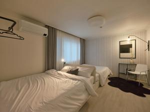 a hotel room with two beds and a chair at joyfulstay in Seoul