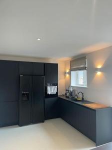 a kitchen with black cabinets and a black refrigerator at Schumis Ferienhus in Garding