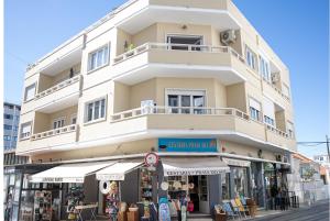 a tall white building with a store front at Capitão Ribeiro Surf House in Costa da Caparica