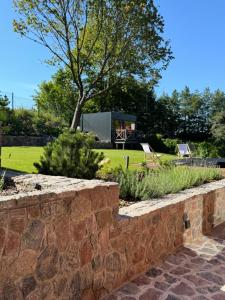 una pared de piedra en un jardín con una casa en Villa D'Jora, en Mikołajki