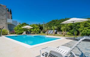 a swimming pool with two chairs and an umbrella at Cozy Apartment In Zaton Veliki in Zaton