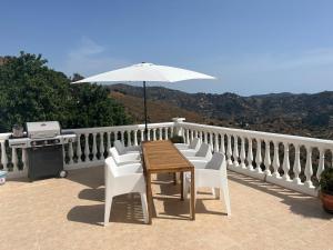 a wooden table and chairs with an umbrella on a balcony at B&B Casa-Bienvenido in Arenas