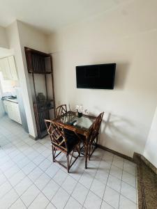 mesa de comedor con sillas y TV en la pared en Flat encantador beira mar na Barra . Em frente a praia! No Circuito do Carnaval de Salvador!, en Salvador