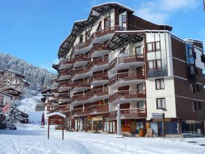 a large building in the snow with snow covered ground at Studio lumineux avec balcon sud, plein cœur de La Tania, skis aux pieds - FR-1-513-43 in La Tania