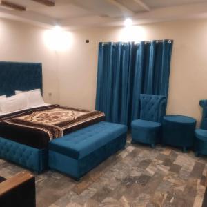 ein Schlafzimmer mit einem Bett und zwei blauen Stühlen in der Unterkunft HOTEL DAY IN Empouriem in Lahore