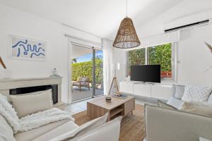 a living room with white furniture and a tv at Ivy Blue Villa by Nomads - Short Walk to Coral Bay in Peyia