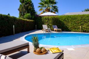 a swimming pool with two chairs and an umbrella at Ivy Blue Villa by Nomads - Short Walk to Coral Bay in Peyia