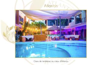 a picture of a swimming pool with tables and chairs at Hotel l'ATLANTYS in Yopougon-Attié