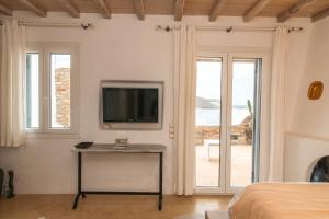 a bedroom with a television and a table with a table at Panormos Art Villas & Suites in Panormos