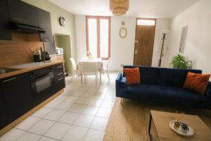Una sala de estar con un sofá azul y una cocina. en Le petit Monlogis - Calme - Wi-Fi, en Angulema