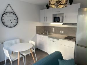 a kitchen with a table and a clock on the wall at L'appartement Bleu-T2-Annemasse in Annemasse