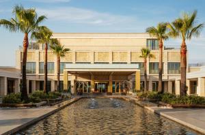 a building with palm trees in front of a pool at Victoria Golf Resort and Spa Managed by Accor in Vilamoura