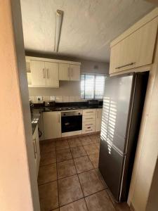 Una cocina con gabinetes blancos y un refrigerador de acero inoxidable. en 58 Chakas Rock Chalets, en Ballito 5 fotos más