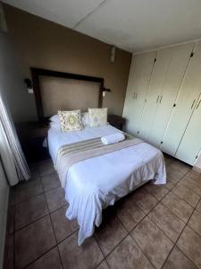 un dormitorio con una cama con sábanas y almohadas blancas en 58 Chakas Rock Chalets, en Ballito