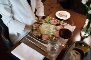 a person sitting at a table with a plate of food at Hotel la Palma au Lac in Locarno
