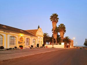 a building with palm trees in front of a street at Hotel Prinzessin Rupprecht in Swakopmund