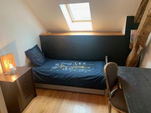 a bedroom with a bed and a desk and a window at La Maison du Pas Trop in Athie
