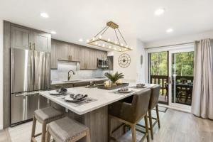 a kitchen with a large kitchen island with chairs at Designer 2 BR on River with Pool - Walk to Town! in Aspen +72 photos