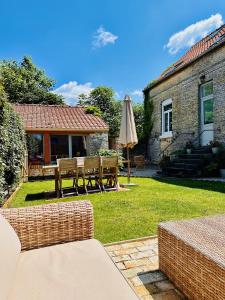a patio with a table and an umbrella in a yard at Duplex Cosy et Bohème avec parking proche Calais in Coulogne