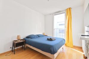 une chambre avec un lit avec des draps bleus et une fenêtre dans l'établissement Appartement Quartier Tour Eiffel 6 Free Netflix, à Paris