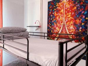 a bed in a room with a painting on the wall at Rainbow Villa, One bed in shared dormitory room, please choose male or female room correctly, not mixed, check in from 16h00 to 23h50 in Villejuif