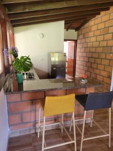 a kitchen with a counter with two chairs and a refrigerator at La Pascana Ecolodge frente al parque Arví Entorno natural excepcional, reserva natural, áreas protegidas, conexión con la naturaleza y avistamiento de aves a 3km del metrocable Guarne in Guarne +10 photos