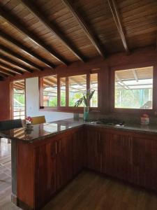 a large kitchen with wooden cabinets and a large island at La Pascana Ecolodge frente al parque Arví Entorno natural excepcional, reserva natural, áreas protegidas, conexión con la naturaleza y avistamiento de aves a 3km del metrocable Guarne in Guarne